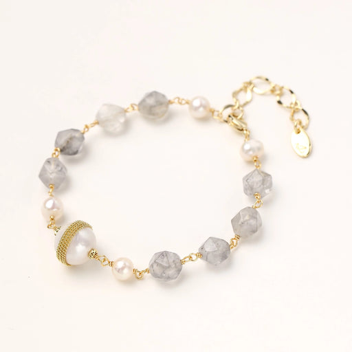 Bracelet with cloudy quartz beads, freshwater pearls, and gold-wrapped baroque pearl centerpiece on white background.