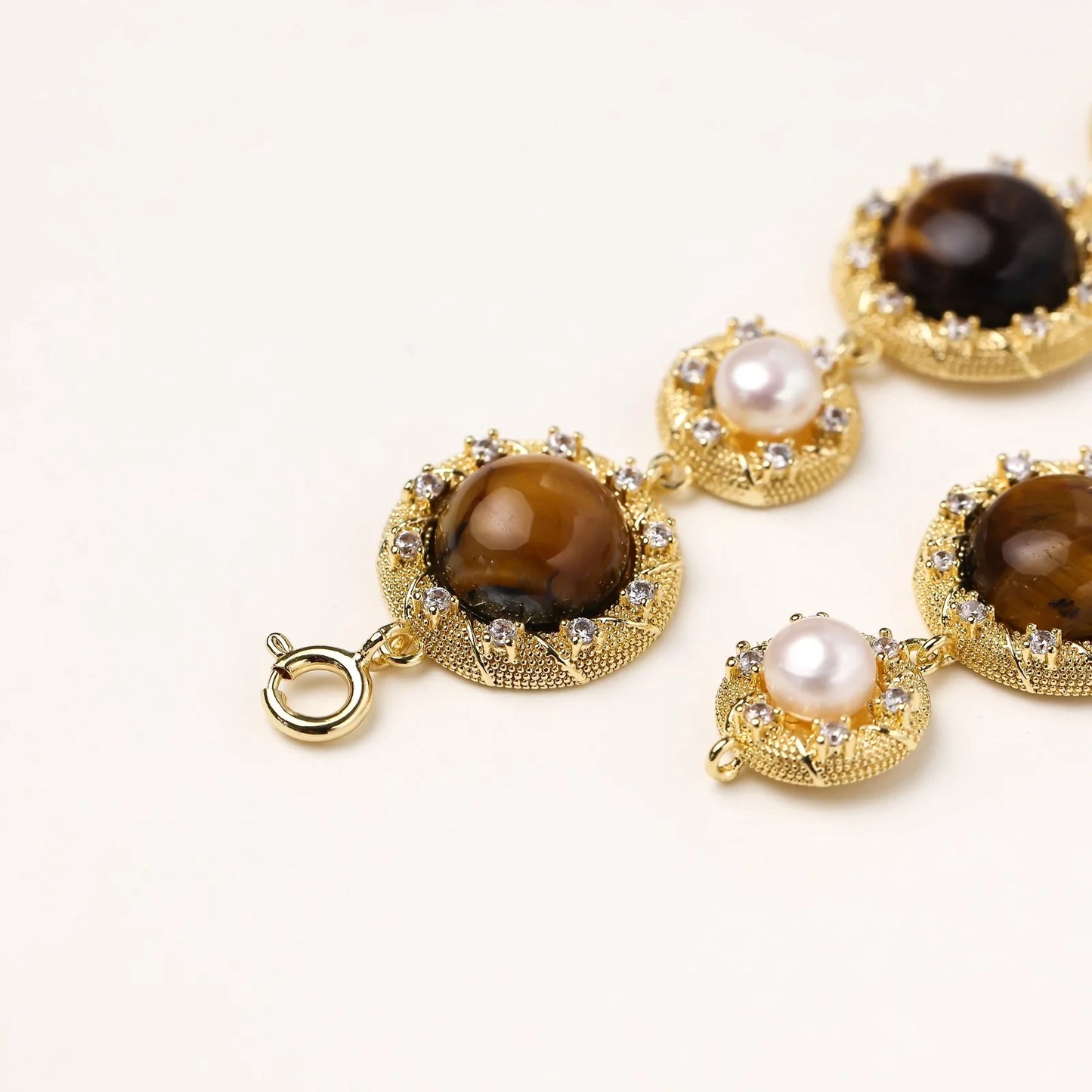 Gold-plated link bracelet with alternating brown tiger's eye stones and white freshwater pearls in ornate bezels.