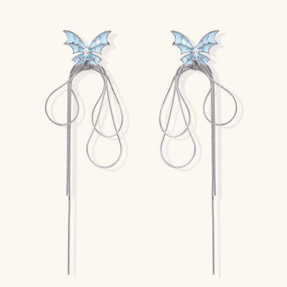 Long silver-tone earrings with powder blue enamel butterfly studs and flowing chain tassels on cream background