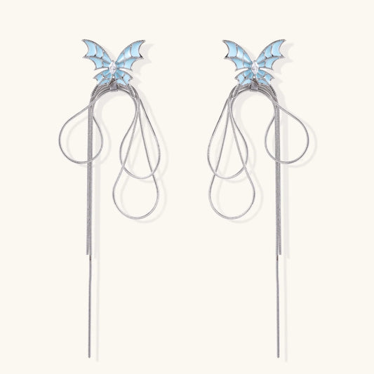 Long silver-tone earrings with powder blue enamel butterfly studs and flowing chain tassels on cream background