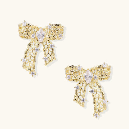 Filigree bow-shaped earrings with marquise center stone and lattice ribbon tails in gold and silver finishes