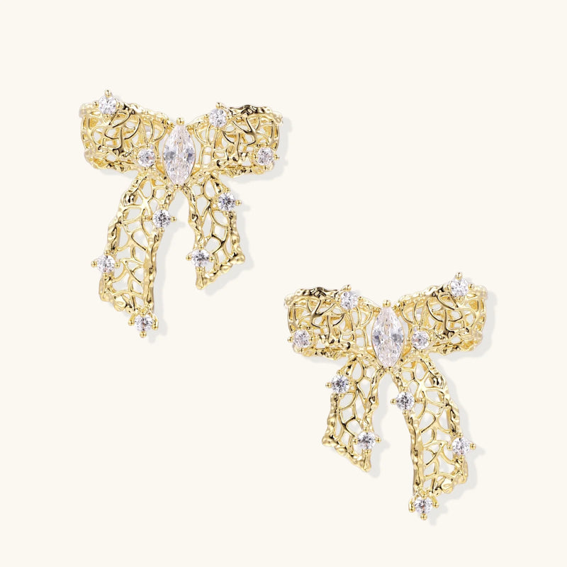 A close-up view of the Ribbon Dreams Bow Earrings by Astral Signature, showcasing their intricate 18K Gold Plated Eco-Brass design, adorned with zirconia, making them perfect Eco-Brass Earrings and a wonderful Gift for Her. Features Sterling Silver (S925) posts for comfort.
