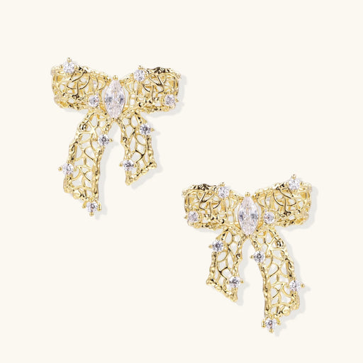 A close-up view of the Ribbon Dreams Bow Earrings by Astral Signature, showcasing their intricate 18K Gold Plated Eco-Brass design, adorned with zirconia, making them perfect Eco-Brass Earrings and a wonderful Gift for Her. Features Sterling Silver (S925) posts for comfort.