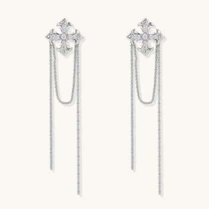White gold plated baroque cross stud earrings with long cascading zirconia chains on cream background