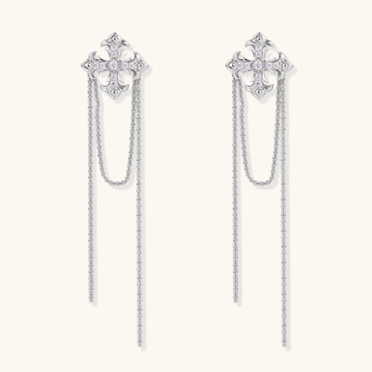 White gold plated baroque cross stud earrings with long cascading zirconia chains on cream background