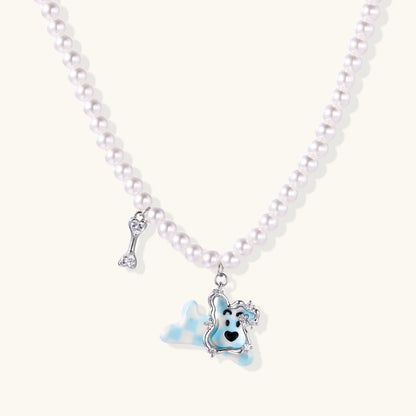 Pearl necklace with playful blue dog pendant accented with sparkly crystals on cream background.