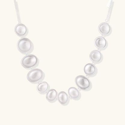 The stunning Lunar Pearl Arc Necklace - Sterling Silver by Astral Signature displayed against a neutral background, highlighting its impressive pearlescent design. An elegant addition to any jewelry collection, this limited edition piece is a great gift for her.