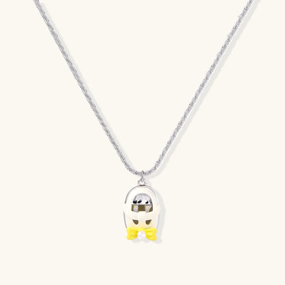 Chrome egg-shaped pendant with kawaii face, yellow bow, and pearl detail on silver chain against white background