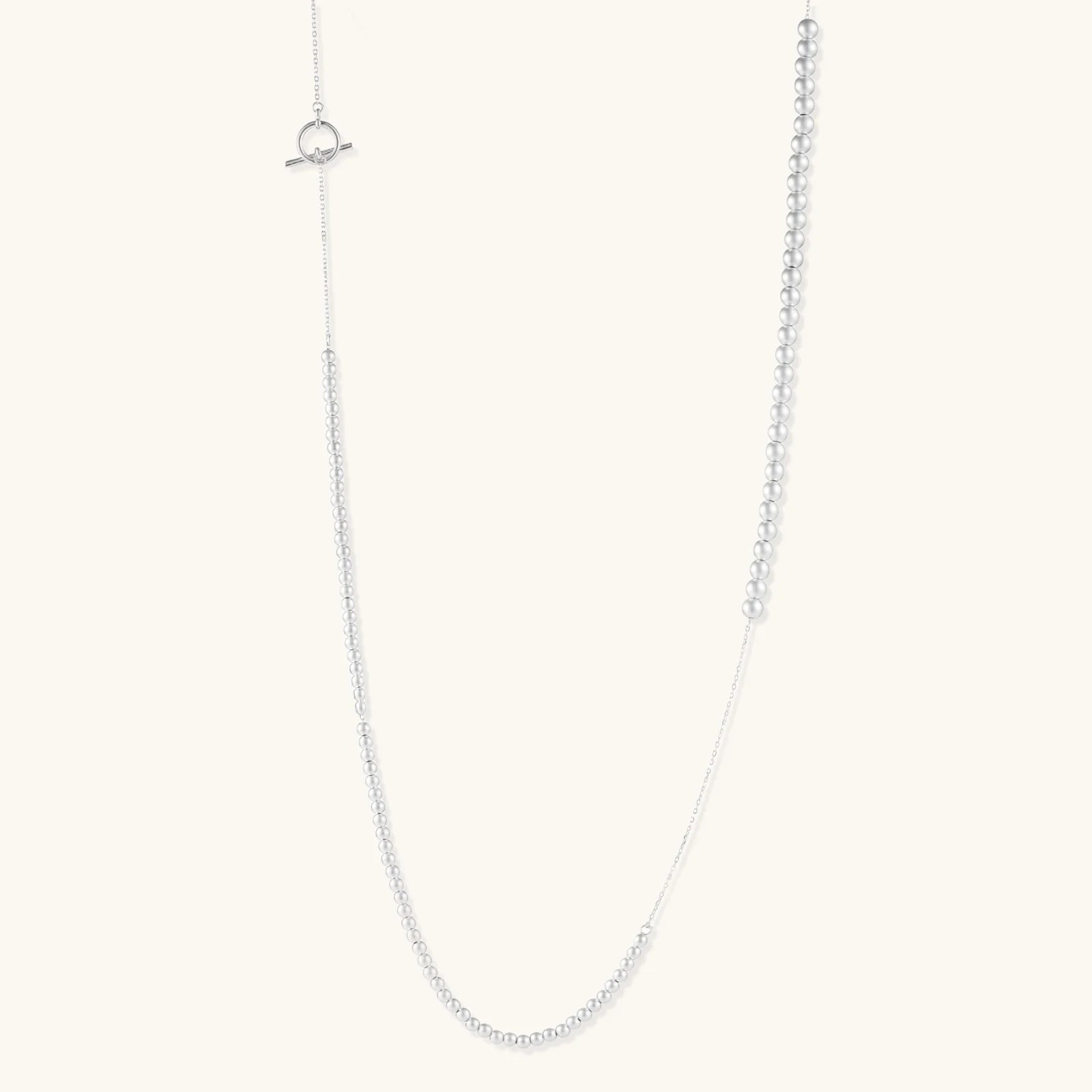 Long sterling silver beaded necklace with graduated sphere design, toggle clasp, and delicate chain extension on white background