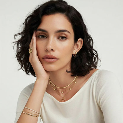 A stylish model showcasing the Golden Crescent Layer Set Necklace by Astral Signature, featuring layers of 14K gold-plated accents, perfect for everyday wear or as a gift for her. This limited edition piece radiates elegance and individuality, making it a must-have accessory.