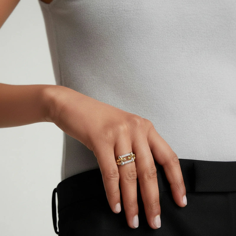 A fashionable image of a woman's hand adorned with the Chain Link Power Ring by Astral Signature. The ring features an intricate design with metallic accents, perfect for adding a touch of sophistication to everyday wear, making it a great gift for her. Part of the limited edition collection by Astral Design.