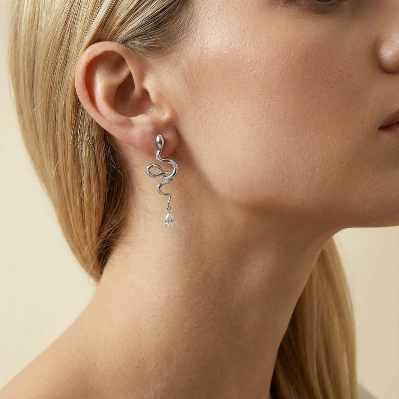 Model showcasing the Serpentine Crystal Drops earrings by Astral Signature, emphasizing drops made from Eco-Brass. The White Gold Plated Eco-Brass earrings are adorned with zirconia and feature Sterling Silver (S925) posts for comfort.