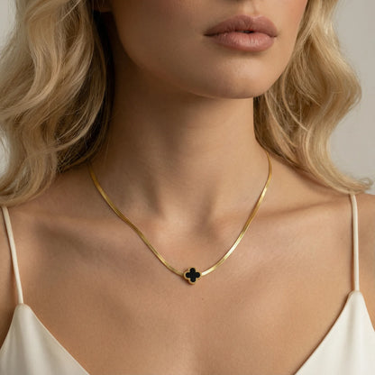 Close-up of a woman wearing the Lucky Clover Necklace by Astral Signature, featuring a black enamel clover pendant on a sleek gold chain, perfect for everyday wear, a gift for her, and available in limited edition. Discover this unique Astral Design.