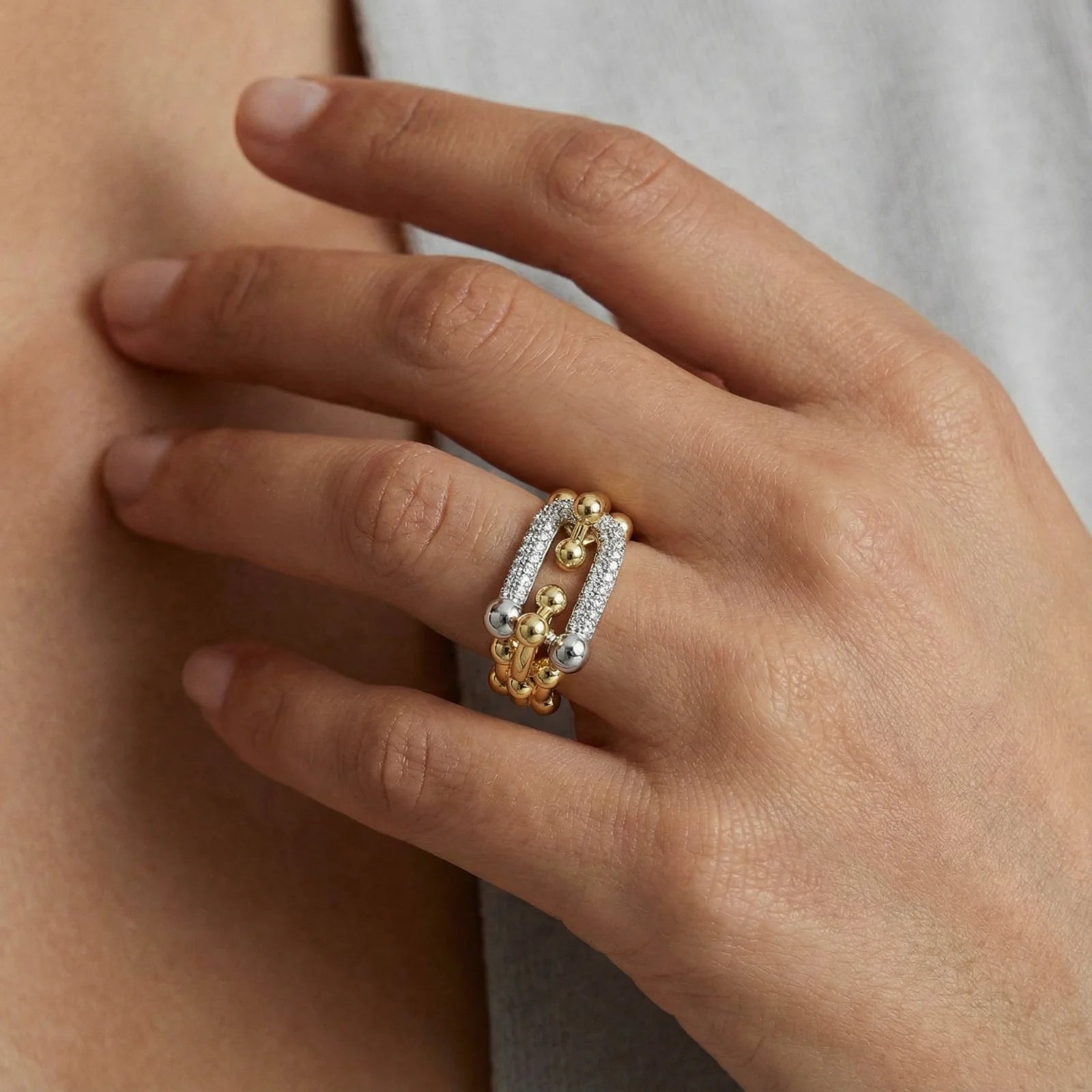 A detailed shot of the Chain Link Power Ring by Astral Signature, emphasizing its unique interlinked design and sparkling stones. This ring is designed for everyday elegance and makes an excellent gift for her, showcasing a stylish blend of gold and silver elements, part of the limited edition by Astral Design.