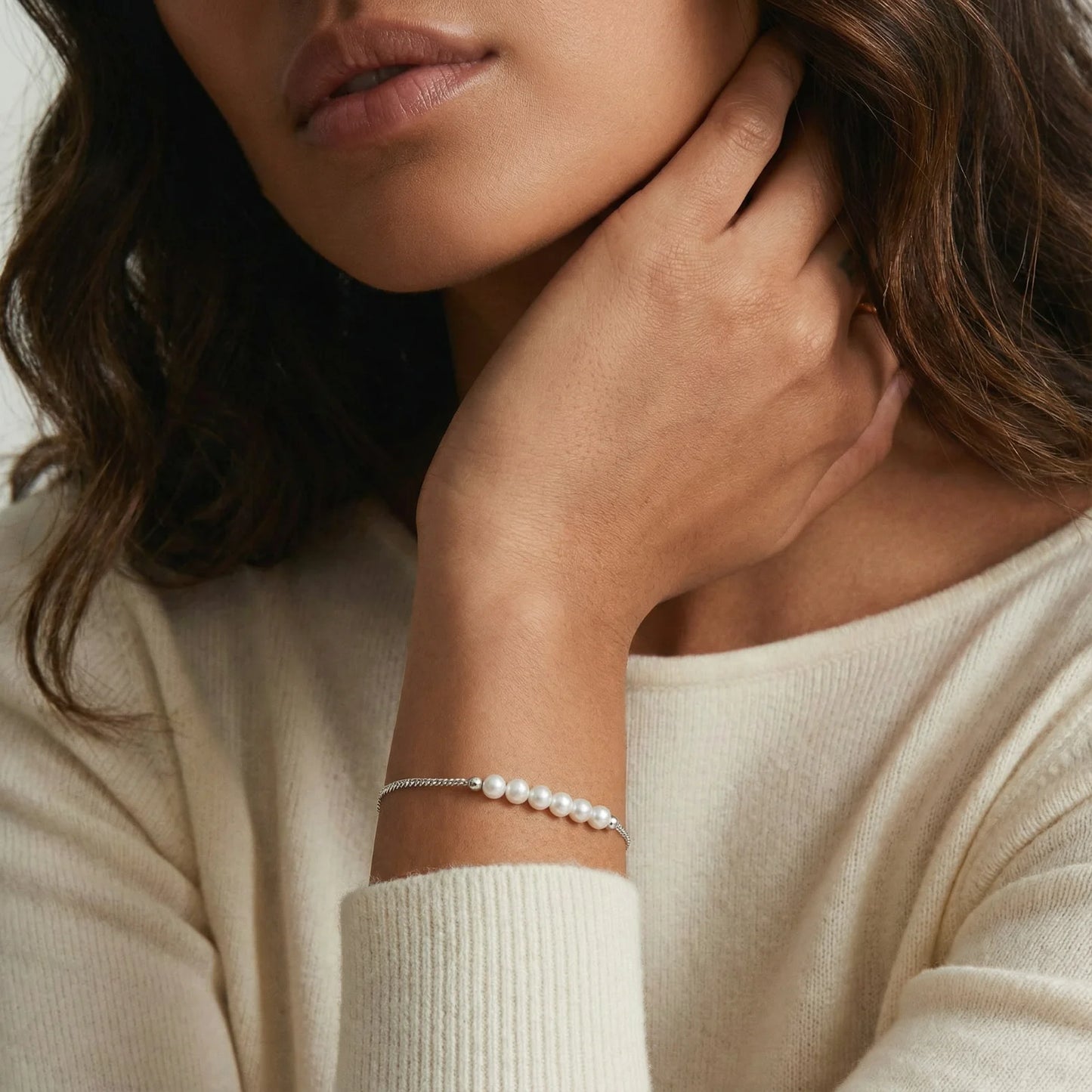 A woman gently holding her chin while wearing the Pearl Whisper Bracelet by Astral Signature, emphasizing the beauty of the baroque pearls set in rhodium-plated silver. This bracelet is perfect for everyday wear, thoughtful gifts for friends or her, and embodies the signature style of Astral Design in a limited edition.