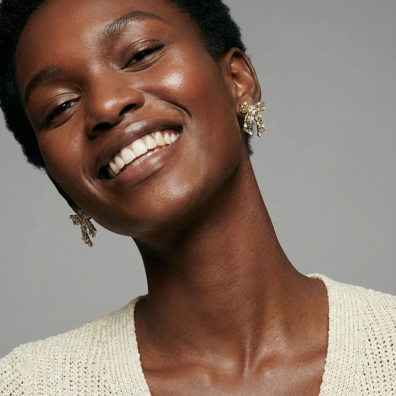 Another model displaying the dazzling Ribbon Dreams Bow Earrings by Astral Signature, designed in 18K Gold Plated Eco-Brass with sparkling zirconia accents. These earrings serve as chic Eco-Brass Earrings and an exquisite Gift for Her, complete with Sterling Silver (S925) posts.