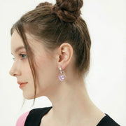 Side view of a woman wearing Pink Heart Drop Hoops by Astral Signature, beautifully designed with pink zirconia. These Eco-Brass earrings are a perfect gift for her, offering a stylish touch with White Gold Plated Eco-Brass.
