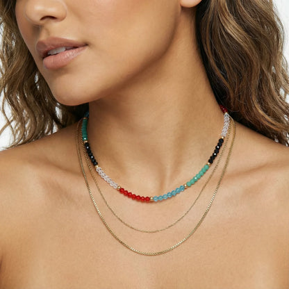 A model displays the Rainbow Aura Layers necklace by Astral Signature, made of colorful beads and 14K Gold Plated Stainless Steel. This beautiful accessory is ideal for everyday wear and serves as a fabulous gift for her, being part of a limited edition collection that highlights the enchanting design.