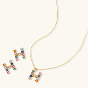 Colorful earrings and pendant necklace of the Crystal H Initial Set by Astral Signature, featuring a playful 'H' design with various gemstones.