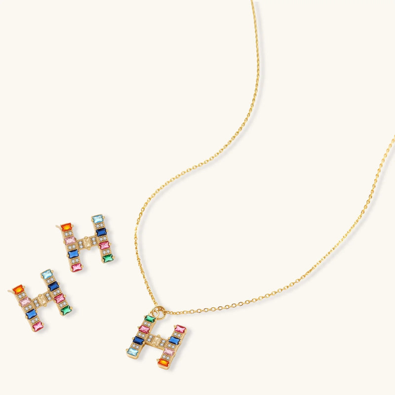 Colorful earrings and pendant necklace of the Crystal H Initial Set by Astral Signature, featuring a playful 'H' design with various gemstones.