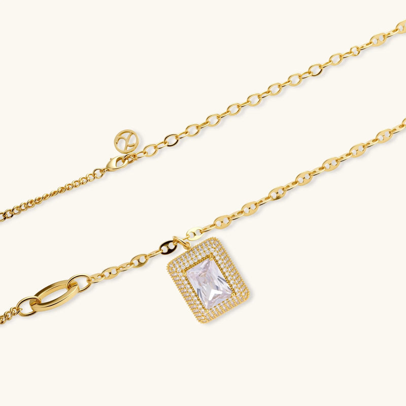 Close-up of the Emerald Cut Halo Set pendant necklace by Astral Signature, highlighting the zirconia stone and intricate detailing in the gold-plated design.