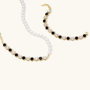 Artistic image of the Astral Signature™ Noir Luxe black and gold jewelry set showing the necklace and bracelet, showcasing the interplay of black and clear zirconia.