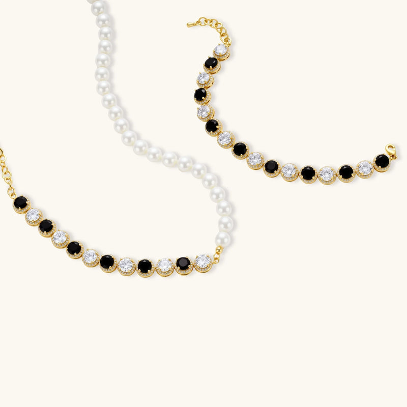 Artistic image of the Astral Signature™ Noir Luxe black and gold jewelry set showing the necklace and bracelet, showcasing the interplay of black and clear zirconia.