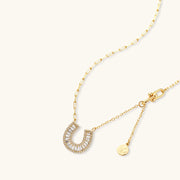 Lustrous gold horseshoe jewelry set with a focus on the necklace, embellished with zirconia, crafted by Astral Signature.