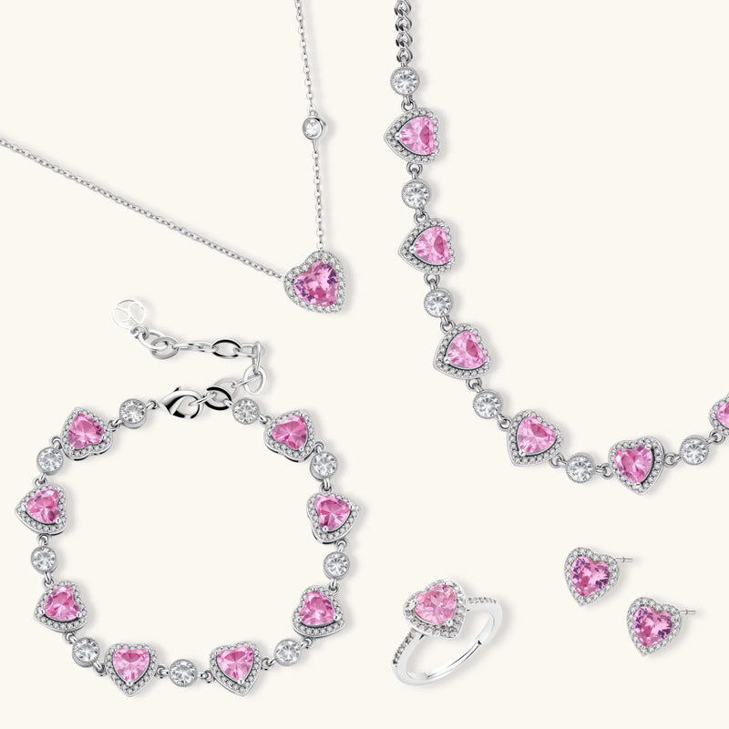 A stunning display of the Romance Heart Set featuring multiple pieces including a necklace, bracelet, and earrings, showcasing pink zirconia hearts surrounded by sparkling accents, from Astral Signature™, a beautiful jewelry collection.