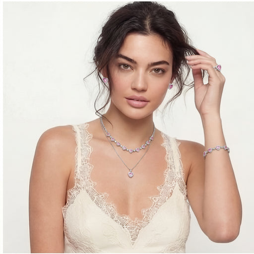 A model elegantly wearing the Romance Heart Set which includes a heart pendant necklace, matching earrings, and a bracelet, displaying a soft pink aesthetic, designed by Astral Signature™, offering a romantic jewelry option.