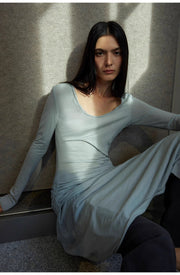 Model seated in a relaxed pose, wearing the Dreamy Ball Wool Dress by PremiumStyle Co.,Limited. The light gray gown’s asymmetric hem highlights a blend of comfort and elegance, marking it as a standout Asymmetric Hem Wool Dress in women's clothing.