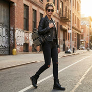 Model showcasing the Studded Backpack with Chain Zipper by HD ACCESSORIES in an urban setting. The bold black and gold design of this handbag adds a trendy touch to any outfit, making it a great addition to your accessories collection.