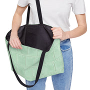 Person holding the Light Green Weekender Tote Bag - Structured Croc-Embossed by Astral Signature, highlighting its roomy black interior. Perfect as a beach tote or vacation tote, this large tote bag combines chic design with practicality for everyday use.