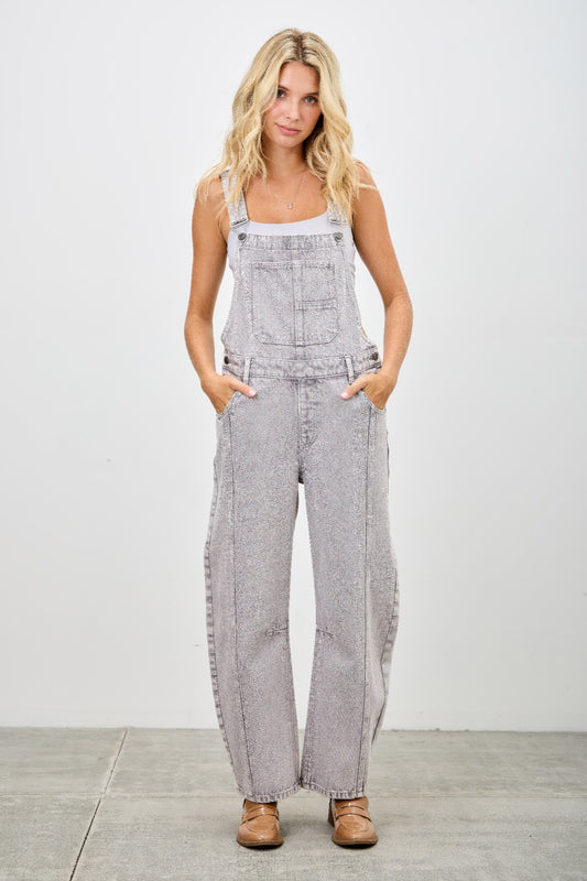 A model showcasing the Barrel Overalls from SAIGE DENIM, featuring a relaxed barrel-leg silhouette in grey, crafted for women's apparel. This stylish jumpsuit combines function and fashion, perfect for versatile styling.