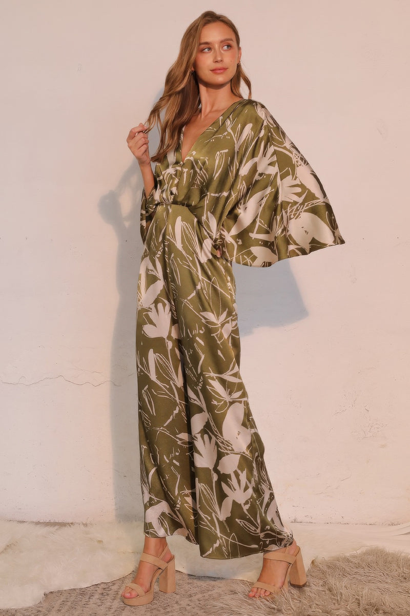 Astral Women's Jumpsuit - Olive Bloom Floral Satin Cape presents a beautiful side view with a dramatic cape overlay, crafted for modern elegance by TYCHE. Perfect for women seeking a unique jumpsuit. APPAREL, CCPRODUCTS, JUMPSUITS & ROMPERS, NEW ARRIVALS, Olive, Satin Cape, Women's Clothing, Women's Jumpsuit, Women’s.