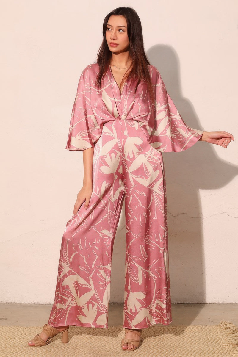 Side view of the Astral Women's Jumpsuit - Dreaming Lily Satin Cape by TYCHE showcasing its elegant cape overlay and chic silhouette in a floral pink design, suitable for upscale occasions. This Women's Jumpsuit is a standout piece in modern women's style. APPAREL, CCPRODUCTS, JUMPSUITS & ROMPERS, NEW ARRIVALS, Pink, Women's, Women's Clothing, Women's Style.