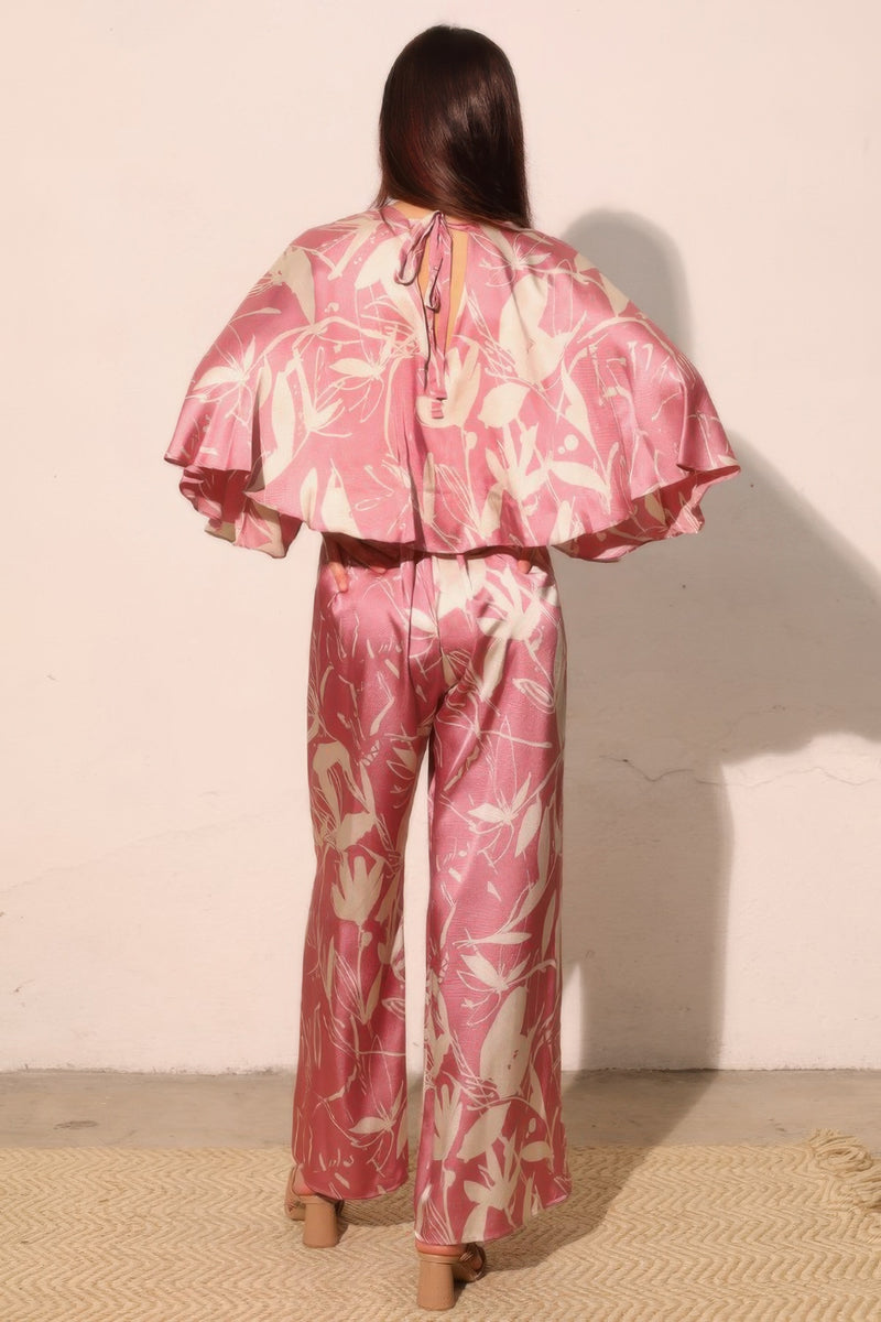 Back view of the Astral Women's Jumpsuit - Dreaming Lily Satin Cape by TYCHE, presenting a stunning cape silhouette that enhances movement and style, perfect for evening wear. This Women's Jumpsuit is an essential piece for refined women's clothing collections. APPAREL, CCPRODUCTS, JUMPSUITS & ROMPERS, NEW ARRIVALS, Pink, Women's, Women's Clothing, Women's Style.