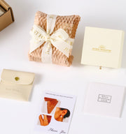 Close-up of the contents in the unboxing of Divine Cascade Earrings by Astral Signature, including care instructions and polishing cloth. A stylish choice as a Gift for Her, these earrings are made with White Gold Plated Eco-Brass and Sterling Silver (S925).