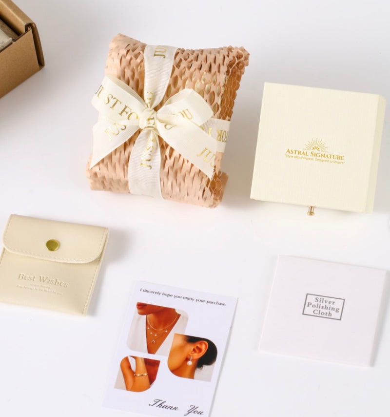 Close-up of the contents in the unboxing of Divine Cascade Earrings by Astral Signature, including care instructions and polishing cloth. A stylish choice as a Gift for Her, these earrings are made with White Gold Plated Eco-Brass and Sterling Silver (S925).