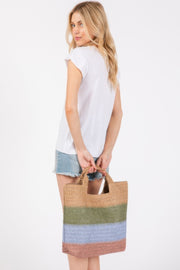 A rear view of a model wearing a white t-shirt and denim shorts, holding the Weekender Stripe Tote Bag by HD ACCESSORIES. The bag displays a stylish blend of blue and green stripes, emphasizing its beach-ready appeal. This tote bag is perfect for summer adventures, making it an essential accessory for any outing. Discover the Weekender Stripe Tote Bag in the new arrivals section.