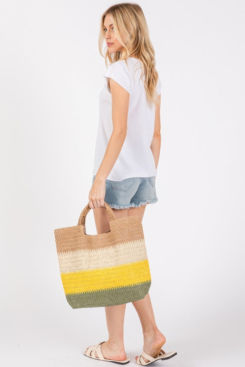 A model walking away in a casual look, showcasing the Weekender Stripe Tote Bag by HD ACCESSORIES. The tote features a delightful combination of mustard, cream, and green shades, making it unique and fun for summer. Perfect for beach trips and outdoor activities, this Weekender Stripe Tote Bag is a must-have accessory among the latest arrivals.