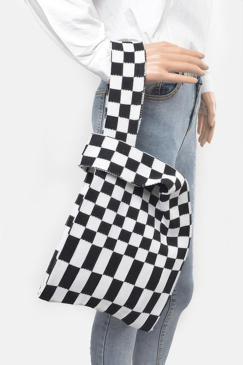 A person carrying a black and white checker pattern Japanese Knot Bag — Chic Checker Woven by HD ACCESSORIES. The image highlights the modern aesthetic of the Japanese Knot Bag Style, ideal for versatile wear and stylish ensembles. ACCESSORIES, Bag, Black, CCPRODUCTS, Chic Checker Poly Woven, HANDBAGS, NEW ARRIVALS.