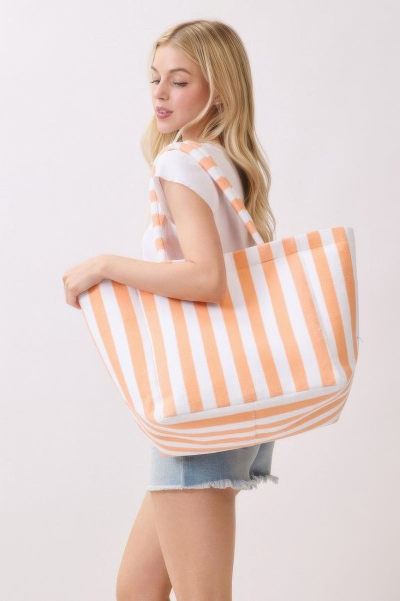 A side view of a woman carrying an orange striped Beach Tote Bag - Striped Tote Bags by HD ACCESSORIES, highlighting the tote's functional design. Ideal for various occasions, this bag is available in colors like Green, Pink green, and Yellow, categorized under HANDBAGS and NEW ARRIVALS.