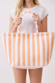 A woman displaying an orange and white striped Beach Tote Bag - Striped Tote Bags from HD ACCESSORIES, emphasizing its spacious interior and plush feel. This versatile bag is a perfect addition to your casual ensemble, available in multiple colors like Green and Pink green. Shop now under ACCESSORIES.