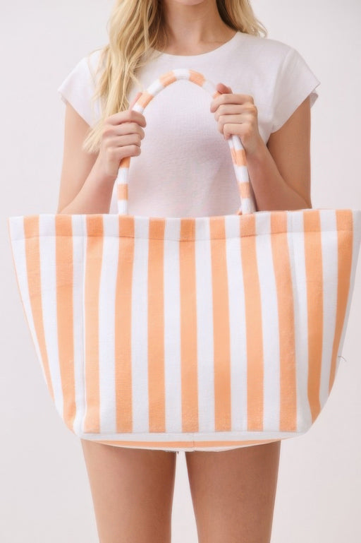 A woman displaying an orange and white striped Beach Tote Bag - Striped Tote Bags from HD ACCESSORIES, emphasizing its spacious interior and plush feel. This versatile bag is a perfect addition to your casual ensemble, available in multiple colors like Green and Pink green. Shop now under ACCESSORIES.