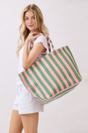 A woman smiling with a pink and green striped Beach Tote Bag - Striped Tote Bags from HD ACCESSORIES, showcasing its stylish handles and functionality. Shop this versatile accessory available in colors like Orange, now part of the HANDBAGS collection.
