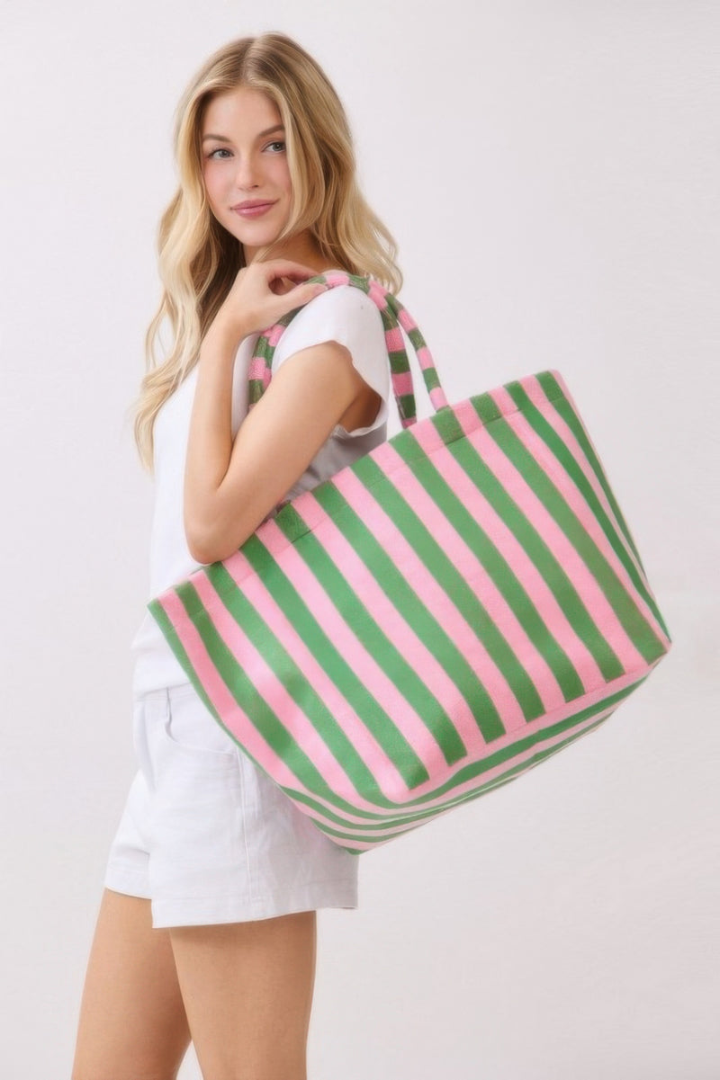 A woman smiling with a pink and green striped Beach Tote Bag - Striped Tote Bags from HD ACCESSORIES, showcasing its stylish handles and functionality. Shop this versatile accessory available in colors like Orange, now part of the HANDBAGS collection.