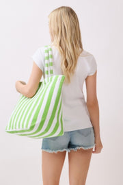 A woman showcasing a light blue striped Beach Tote Bag - Striped Tote Bags from HD ACCESSORIES, emphasizing its chic design. Ideal for everyday use, this bag is available in multiple colors including Green, Orange, and Pink green.