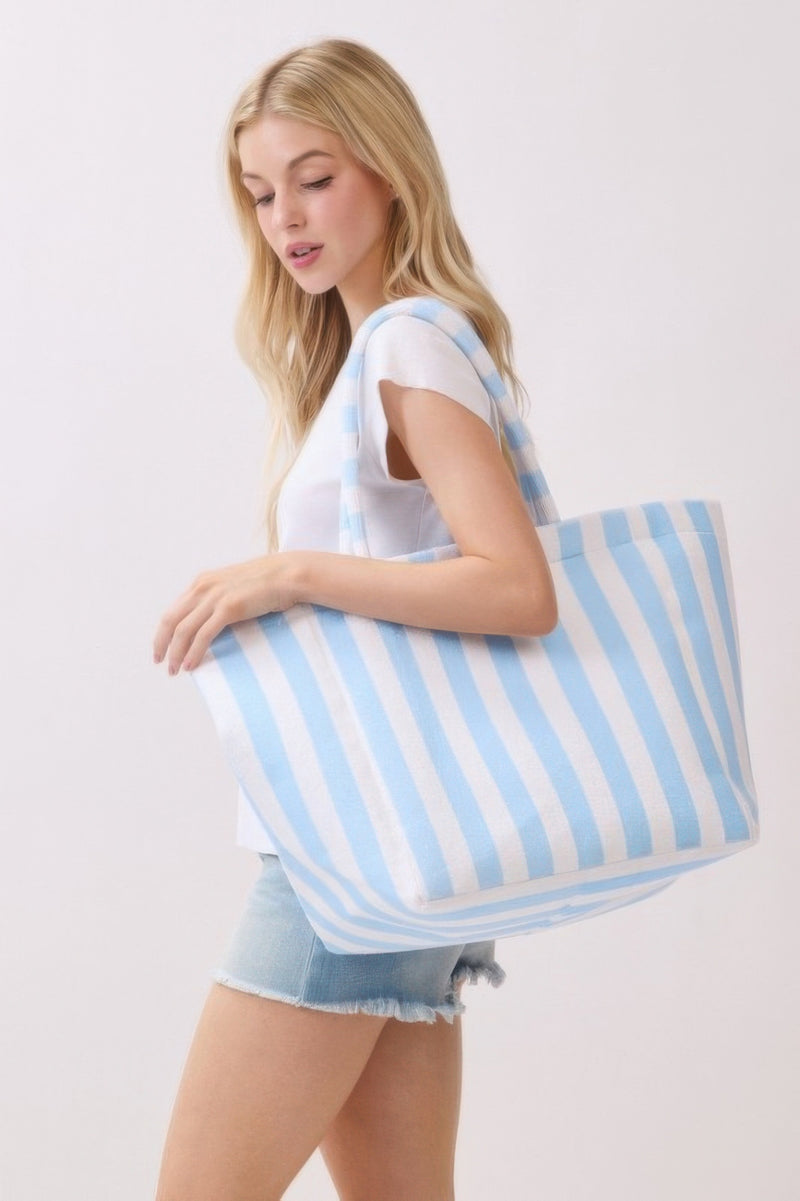 A woman modeling a blue striped Beach Tote Bag - Striped Tote Bags from HD ACCESSORIES, highlighting its stylish appearance and practical size. Perfect for casual outings, this tote comes in various colors like Green and Yellow, categorized under HIP ACCESSORIES.