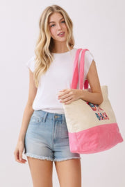 The Life Is Better At The Beach Tote Bag by HD ACCESSORIES is presented in a fashionable way as a model wears it over her shoulder. The vibrant pink color and beach graphics make this tote bag a favorite among summer handbags and accessories. Perfect for new arrivals.